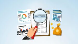 Une main tenant une loupe mettant en avant une feuille de bilan et compte de résultats d'une entreprise. A côté, il y a une calculatrice, une bourse avec les sous, des lunettes pliées et des feuilles de graphiques
