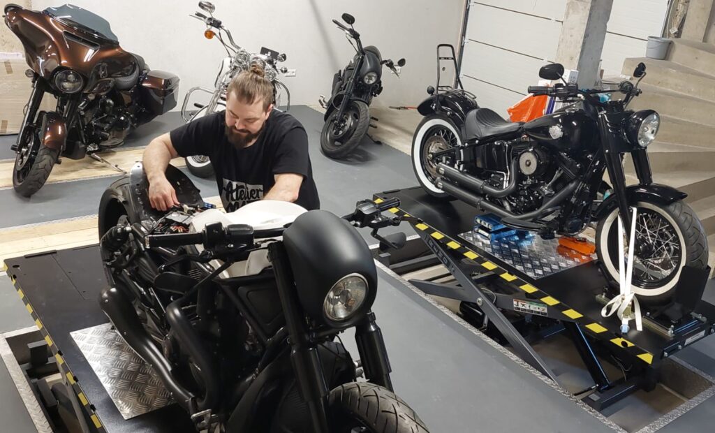 Manu, entrepreneur soutenu par microlux, en train de customiser une moto Harley-Davidson, dans son atelier - Atelier M13